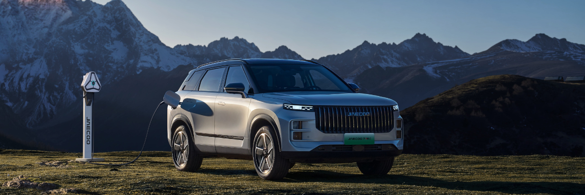 Angebote JAECOO 7 PHEV | Das Bild zeigt einen grauen SUV auf einer Wiese vor einem Bergpanorama.