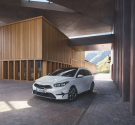 Kia Creed Sportswagon | Das Bild zeigt einen weißen PKW vor einem modernen Gebäude.