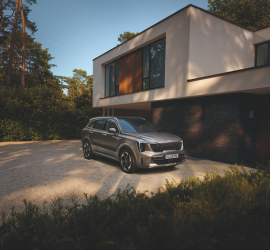 Kia Sorrento Hybrid | Das Bild zeigt einen SUV vor einem modernen Gebäude.