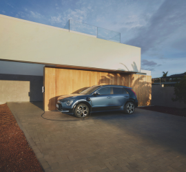 Kia Niro | Das Bild zeigt einen SUV vor einer Garage mit Ladestation.