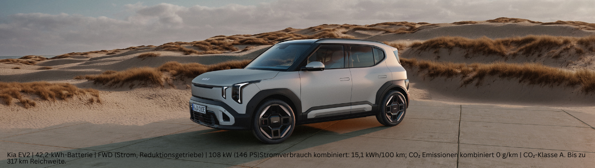 Kia EV2 | Das Bild zeigt einen hellblauen SUV auf einem Parkplatz vor Sanddünen.
