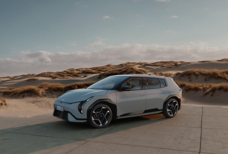 Kia EV4 | Das Bild zeigt einen hellblauen SUV auf einem Parkplatz vor Sanddünen.